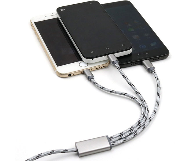 Three-in-one USB charging cable connected to three mobile phones in gold, black, and silver.